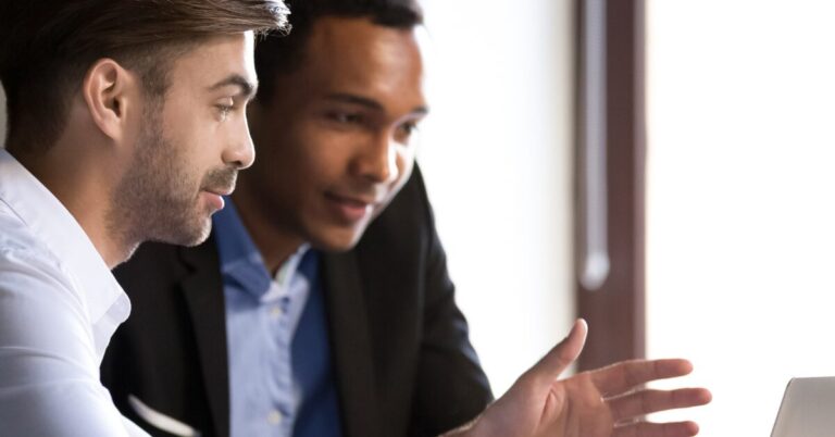Two people having a meeting near a laptop computer